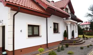 Elegancki dom z białymi ścianami i brązowym cokołem. Podkreśla to, z czego zrobić cokół wokół domu, aby uzyskać taki efekt.