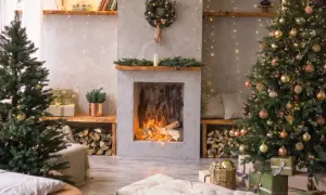 Przytulny salon z dwoma choinkami, kominkiem i prezentami.