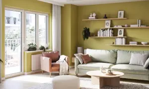 Jasnozielone, modne kolory ścian tworzą przytulną atmosferę w salonie z pastelową sofą i fotelem.