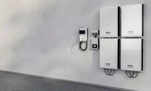Cztery białe magazyny energii na ścianie, obok ładowarka do pojazdów elektrycznych. Zastanawiasz się, magazyn energii 5 kw na ile wystarczy?