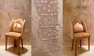 Eleganckie fotele w ciepłych barwach stoją przy ścianach ozdobionych misternymi, tłoczonymi tynkami glinianymi.