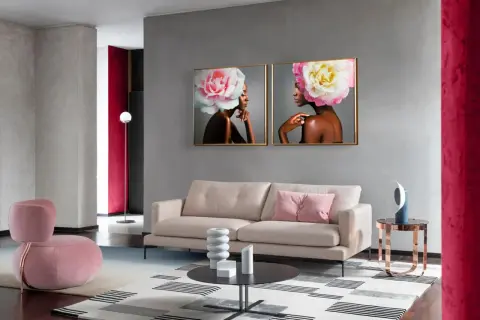 Elegancki salon z sofą, fotelem i obrazami kobiet z kwiatami we włosach. W tle widać ścianę w kolorze magenta.