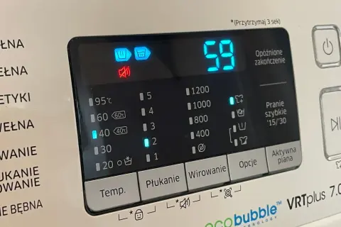 Panel pralki z ikonami i cyfrowym wyświetlaczem. Widoczny symbol prania wstępnego, czas 59 minut i opcje wirowania.