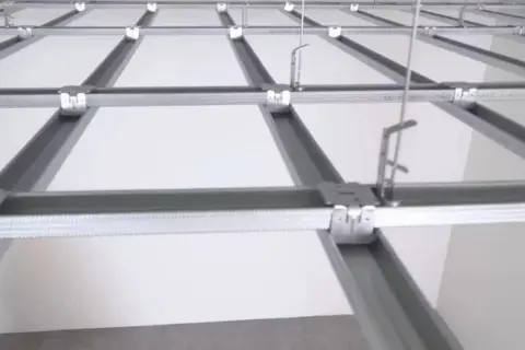 Siatka profili ud podwieszanego sufitu, z widocznymi elementami montażowymi i białymi panelami.