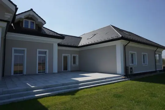 Nowoczesny dom z tarasem i schodami, ozdobiony eleganckimi gzymsami.