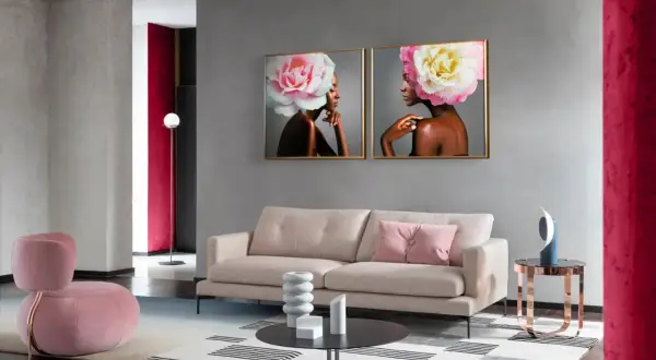 Elegancki salon z sofą, fotelem i obrazami kobiet z kwiatami we włosach. W tle widać ścianę w kolorze magenta.