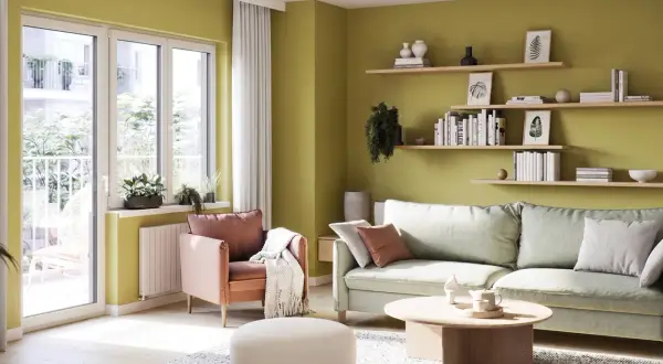 Jasnozielone, modne kolory ścian tworzą przytulną atmosferę w salonie z pastelową sofą i fotelem.