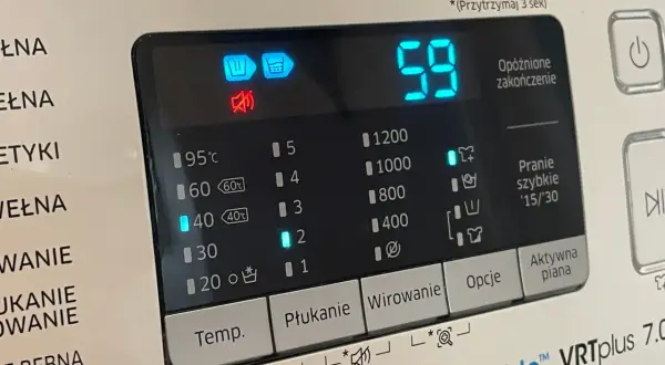 Panel pralki z ikonami i cyfrowym wyświetlaczem. Widoczny symbol prania wstępnego, czas 59 minut i opcje wirowania.