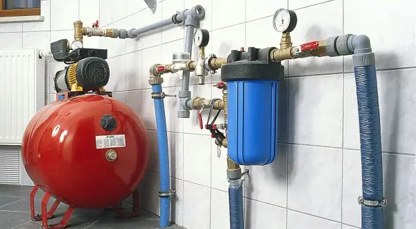 System hydroforowy: czerwony zbiornik, pompa, niebieski filtr wody i manometry. To rozwiązanie zapewnia stałe ciśnienie wody.