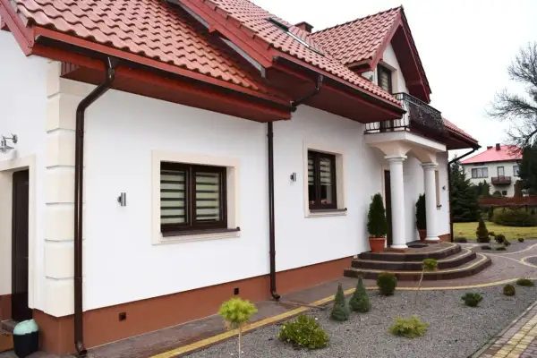 Elegancki dom z białymi ścianami i brązowym cokołem. Podkreśla to, z czego zrobić cokół wokół domu, aby uzyskać taki efekt.