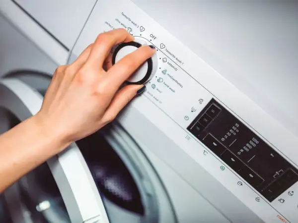 Dłoń ustawia program na pralce, wybierając opcję wirowania.